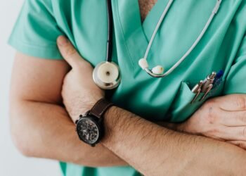 Doctor in scrubs with folded arms and stethoscope, symbolizing confidence in healthcare.