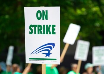 A protest sign with 'On Strike' text held during an outdoor demonstration, highlighting labor movements.