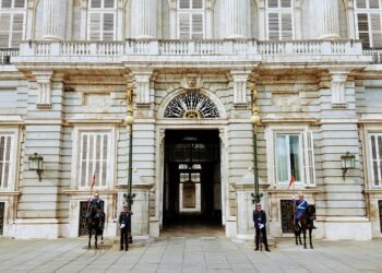 Guards and cavalry stand at the Royal Palace of Madrid entrance, showcasing Spanish heritage.