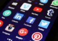 Close-up of a smartphone screen showing various social media app icons such as Facebook and Twitter.