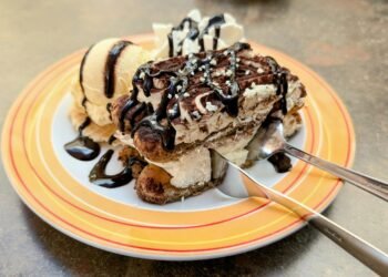 Tiramisu with chocolate drizzle served with vanilla ice cream on a colorful plate, perfect dessert treat.