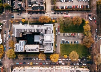 High-angle shot of urban streets and architecture in Belfast, showcasing parked cars and autumn trees.