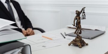 A legal professional's workspace featuring Lady Justice statue, documents, and a laptop.