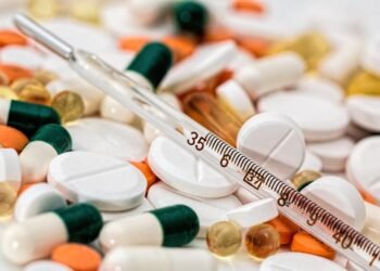 Close-up image showing various pills and a thermometer, emphasizing health and medicine.